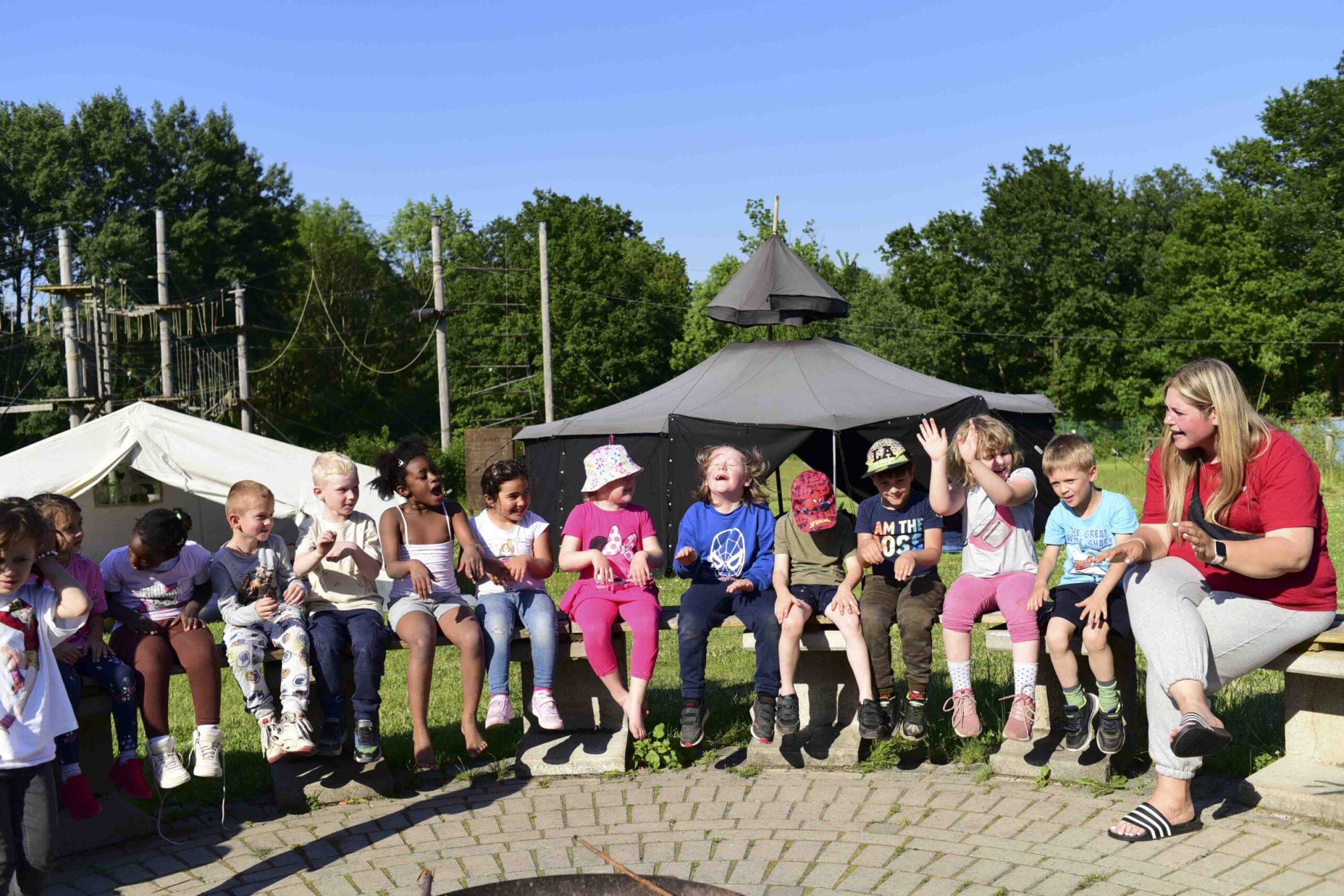 Spielrunde mit Kindern und einer Betreuerin beim Spielen im Sitzkreis